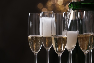 Photo of Pouring champagne into glasses on blurred background, closeup
