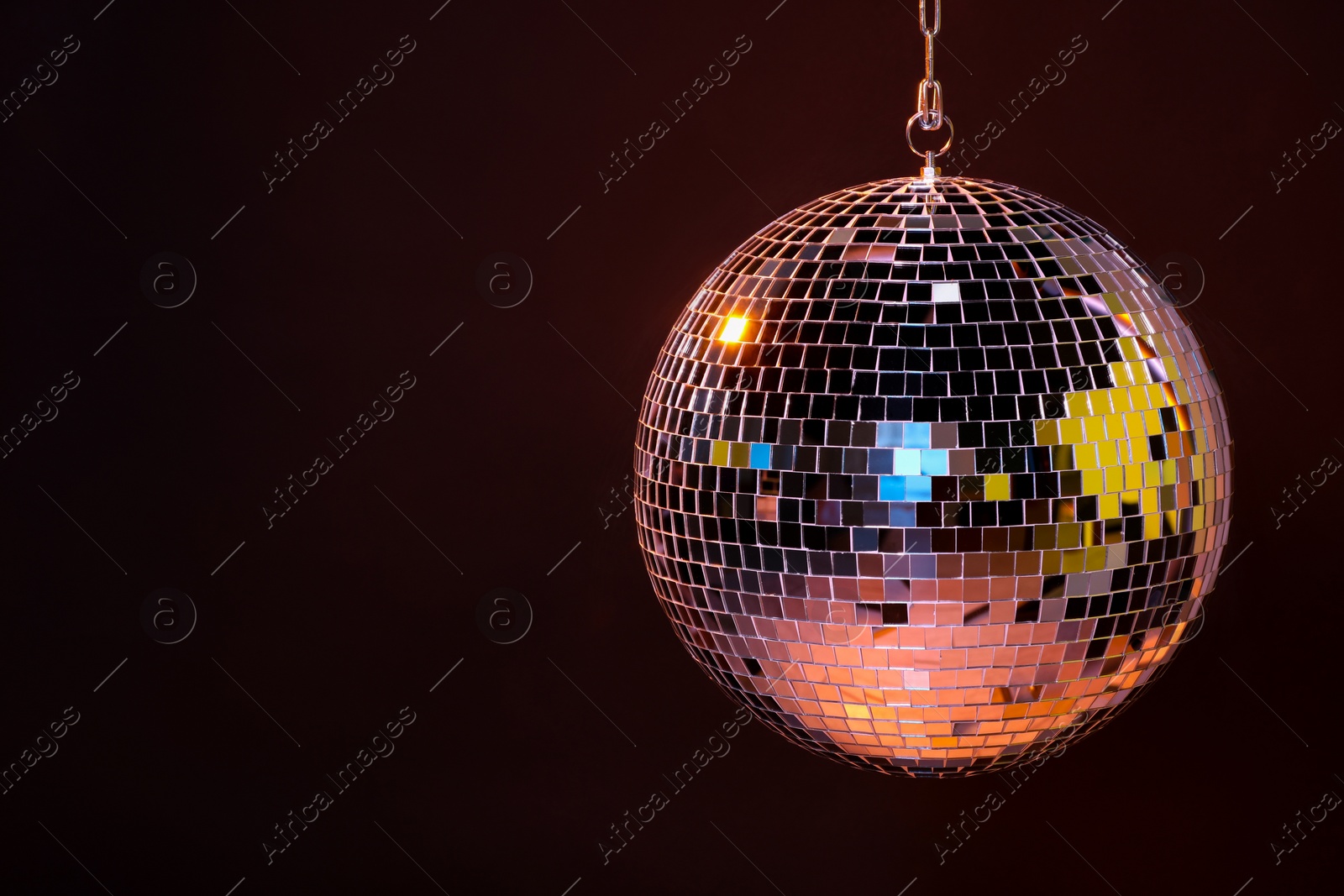 Photo of Shiny bright disco ball on dark background, space for text