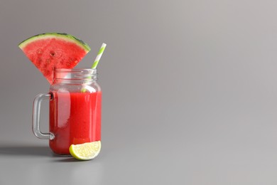 Tasty summer watermelon drink with lime in glass mason jar on grey background. Space for text