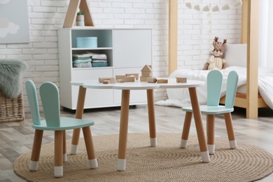 Photo of Little table and chairs with bunny ears in children's room. Interior design