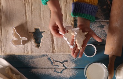 Photo of Little child making Christmas cookies at blue wooden table, top view