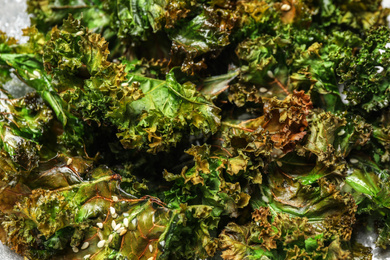 Photo of Tasty baked kale chips as background, closeup