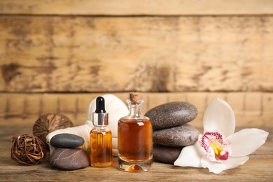 Photo of Beautiful spa composition with essential oil and orchid flower on wooden table, space for text