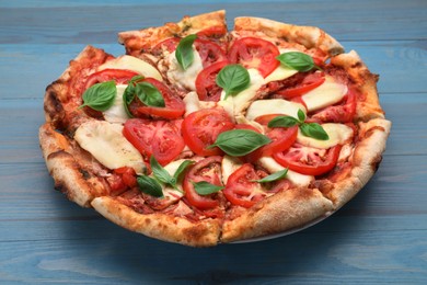 Photo of Delicious Caprese pizza on blue wooden table, closeup