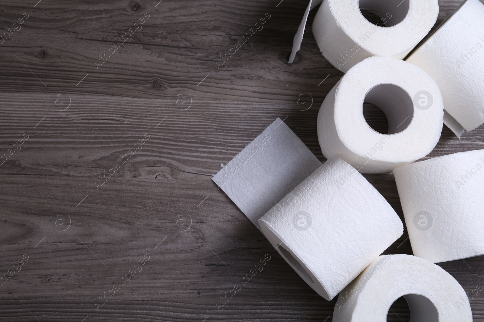 Photo of Soft toilet paper rolls on wooden table, flat lay. Space for text