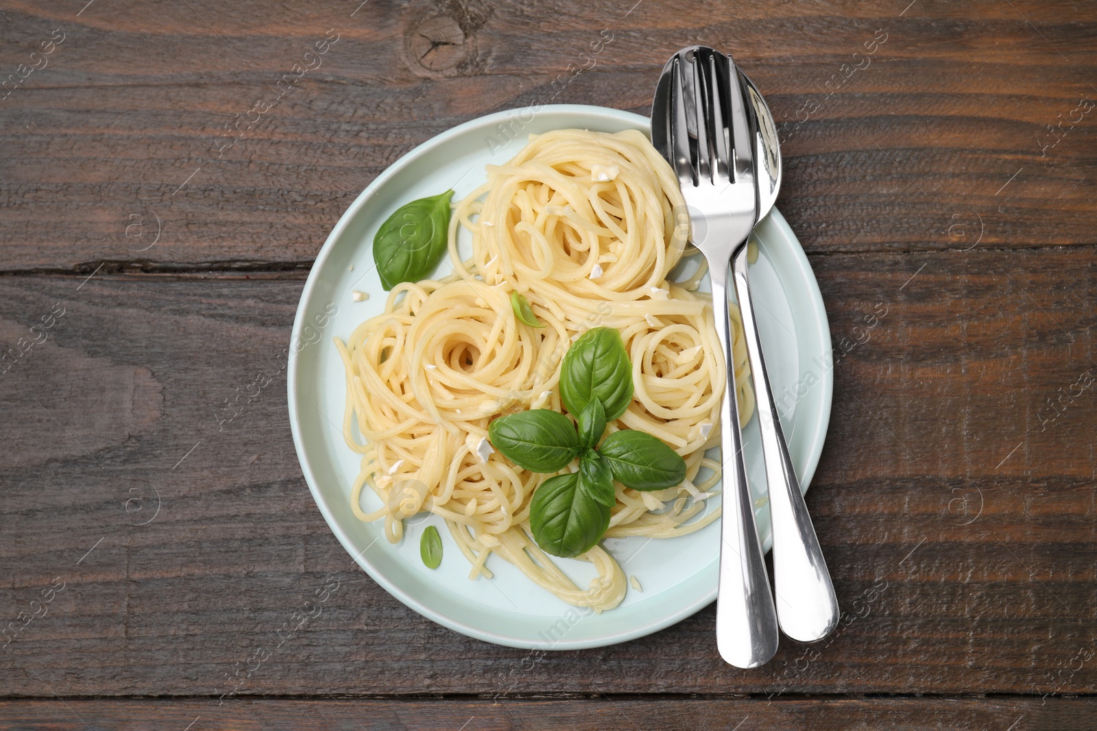 Photo of Delicious pasta with brie cheese and basil leaves on wooden table, top view