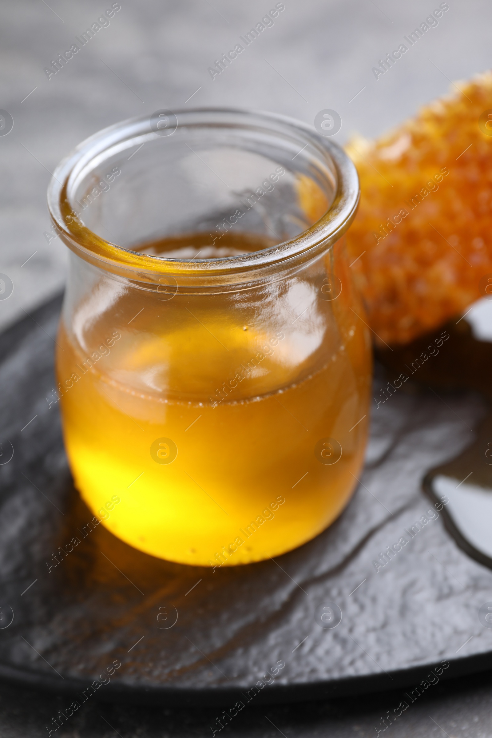 Photo of Tasty aromatic honey and combs on grey table