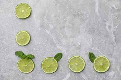 Photo of Flat lay composition with slices of fresh juicy limes on marble table. Space for text