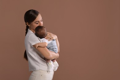 Photo of Mother holding her cute newborn baby on brown background, space for text