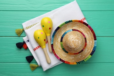 Photo of Mexican sombrero hat, maracas and poncho on turquoise wooden table, flat lay