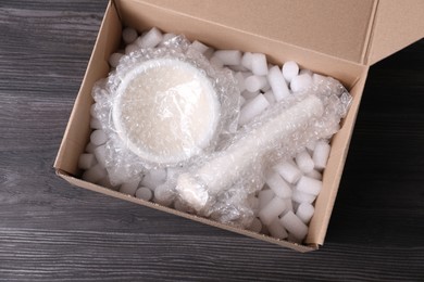 Mortar and pestle with bubble wrap in cardboard box on dark wooden table