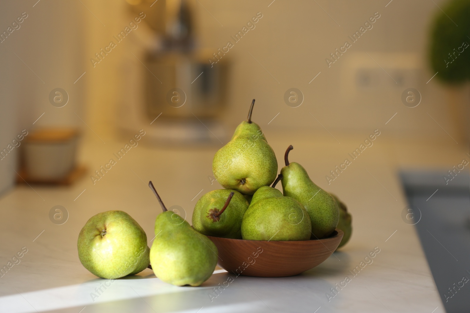 Photo of Fresh ripe pears on white countertop in kitchen