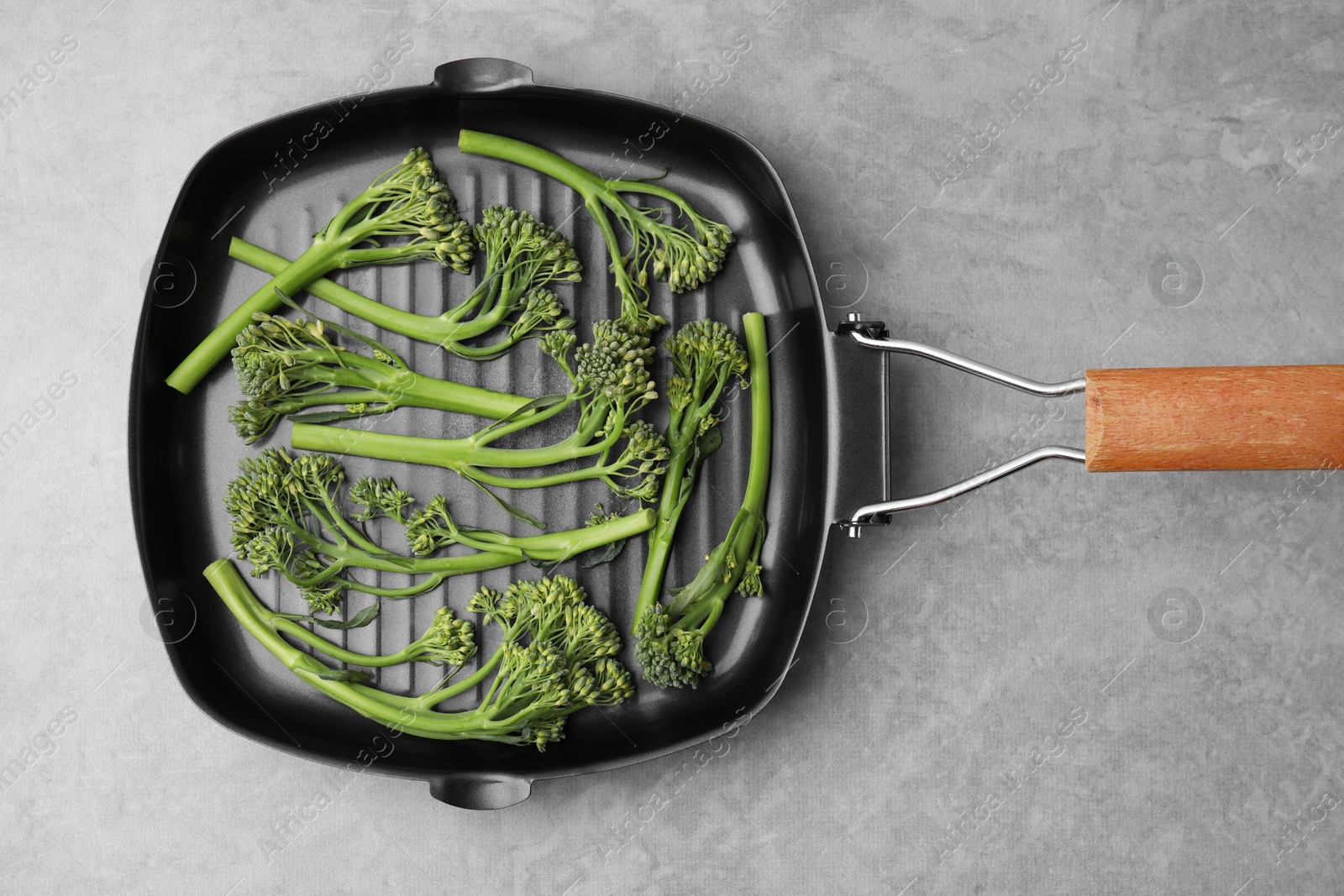 Photo of Pan with fresh raw broccolini on light grey table, top view. Healthy food