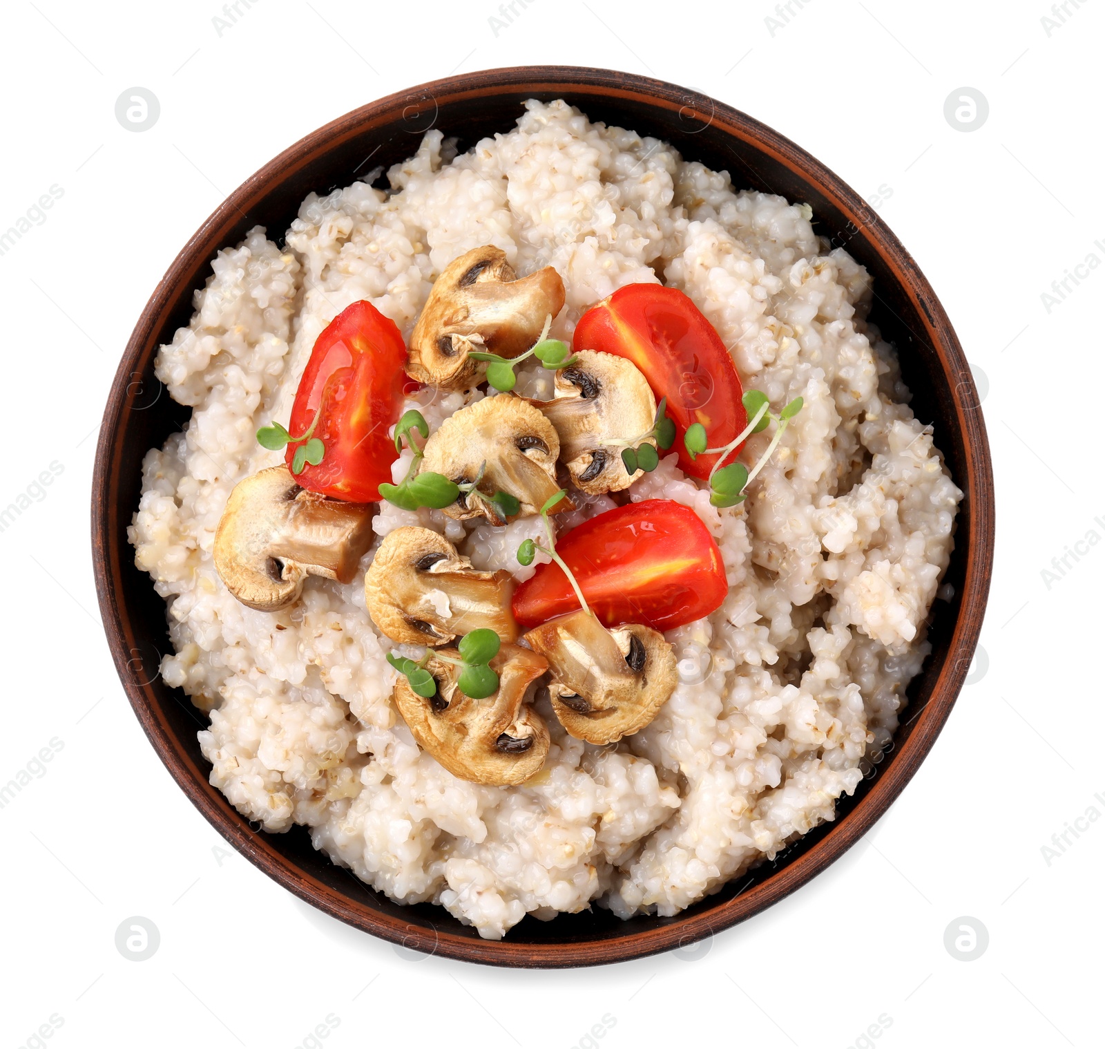 Photo of Delicious barley porridge with mushrooms, tomatoes and microgreens in bowl isolated on white, top view