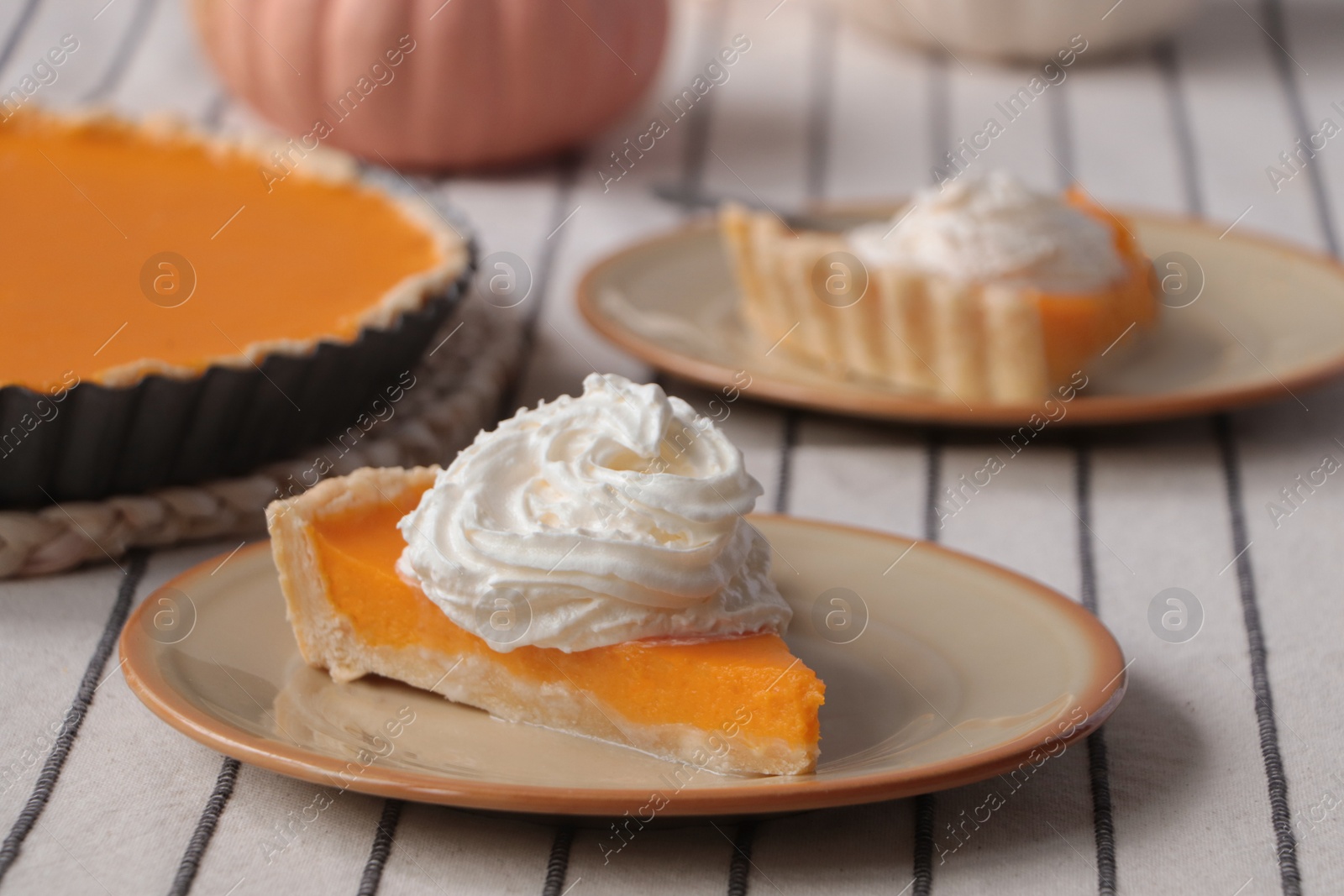 Photo of Piece of fresh homemade pumpkin pie with whipped cream on table