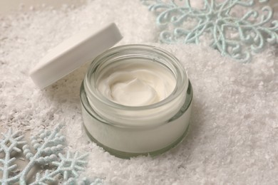 Photo of Winter skin care. Hand cream near decorative snowflakes on artificial snow, closeup