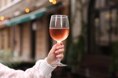 Photo of Woman holding glass of rose wine outdoors, closeup