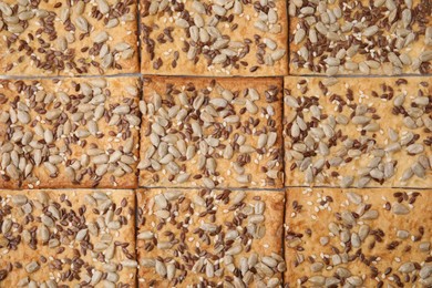 Photo of Cereal crackers with flax, sunflower and sesame seeds as background, top view