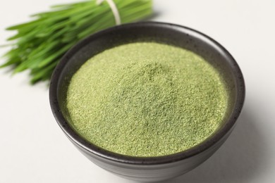 Wheat grass powder in bowl on light table, closeup