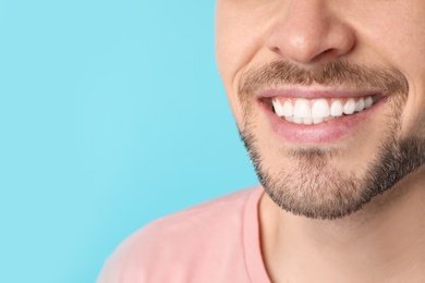 Smiling man with perfect teeth on color background, closeup. Space for text