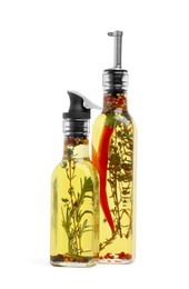 Glass bottles of cooking oils with spices and herbs on white background