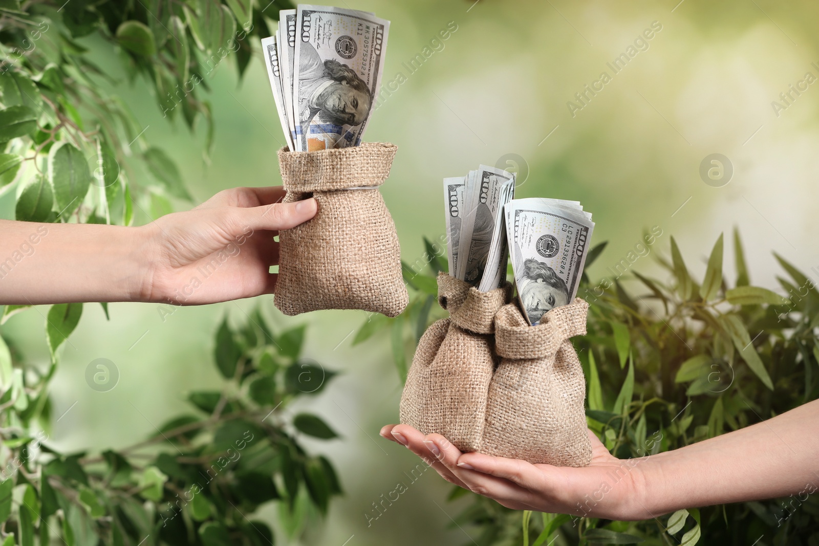 Photo of People holding sacks with dollar bills on blurred background, closeup. Money transfer