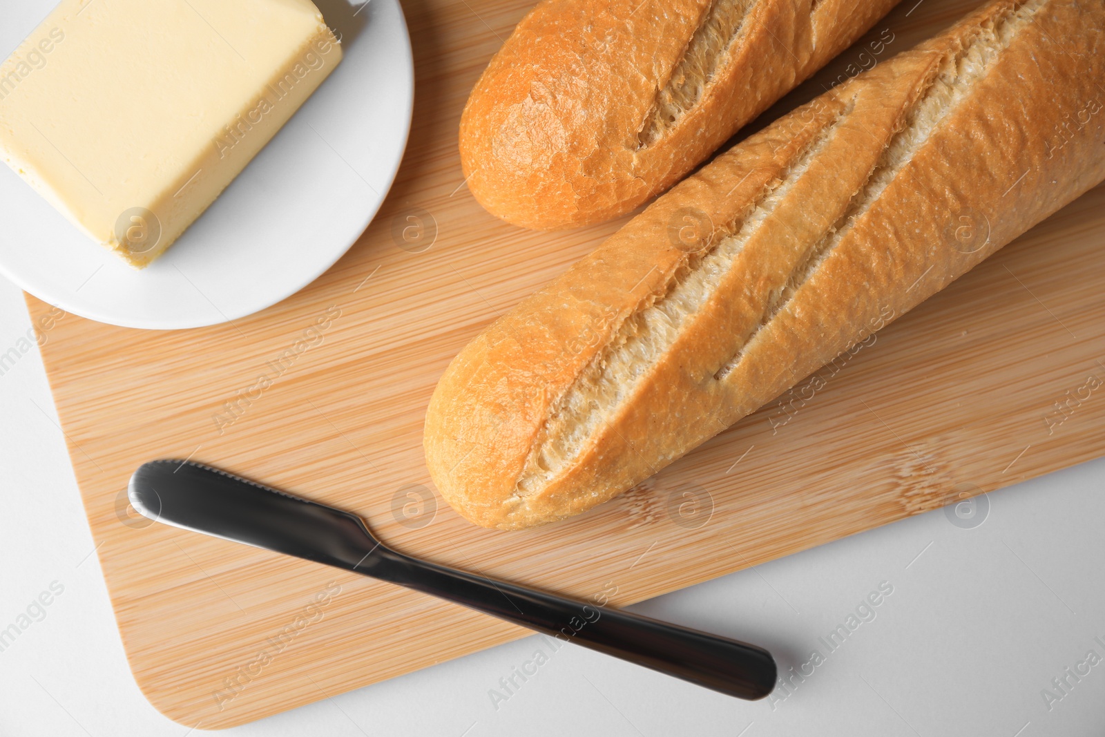 Photo of Tasty baguettes with fresh butter on white table, top view