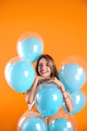 Photo of Young woman with air balloons on color background