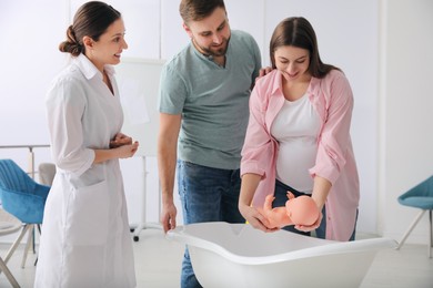 Photo of Man with pregnant wife learning how to bathe baby at courses for expectant parents indoors