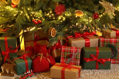 Many gift boxes under Christmas tree in room
