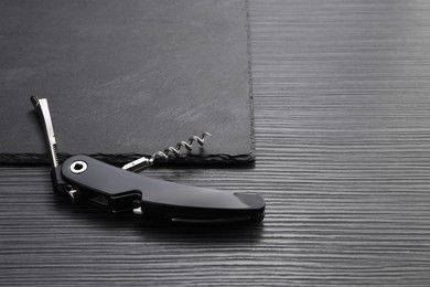 Photo of One corkscrew (sommelier knife) on black wooden table. Space for text