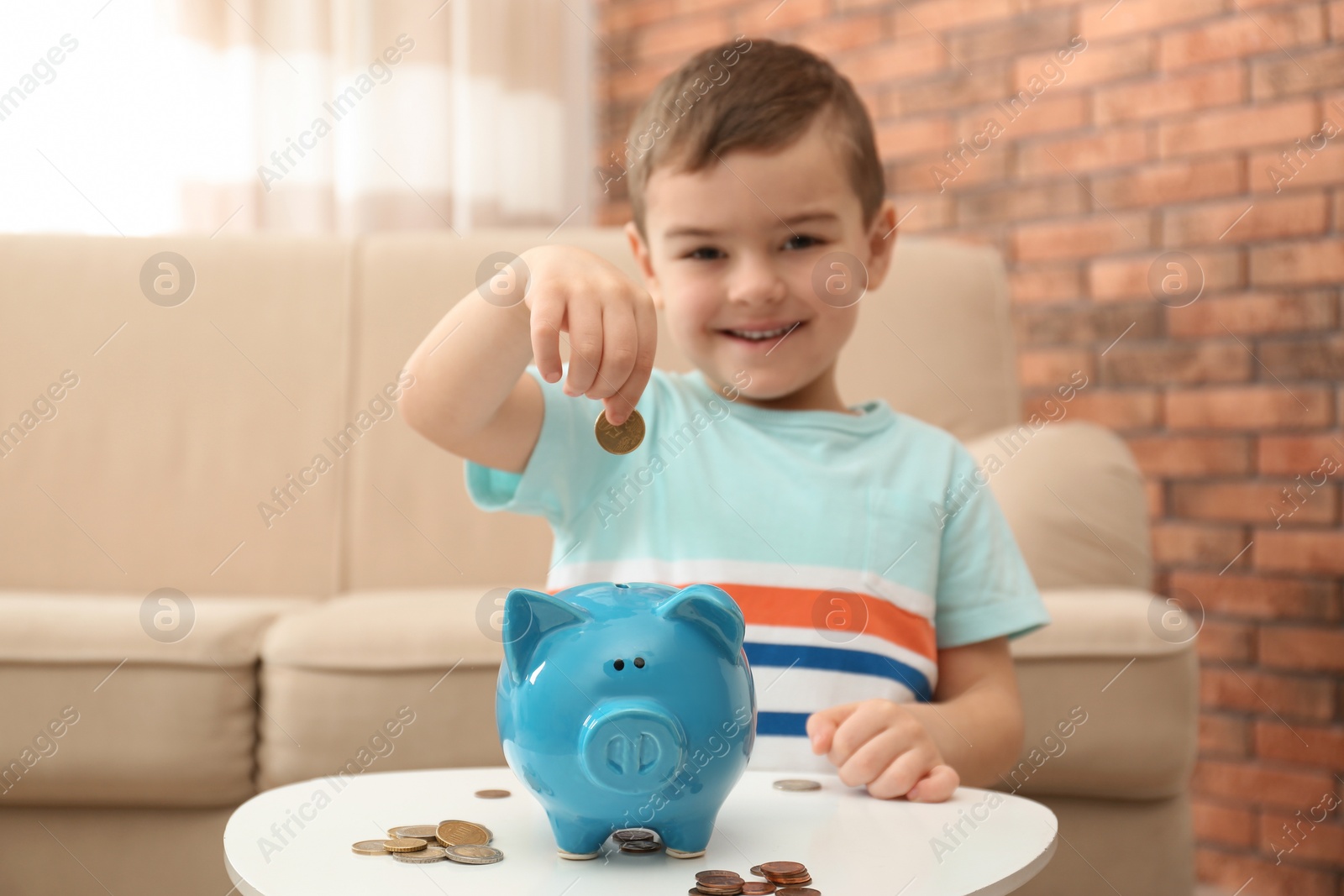 Photo of Little boy with piggy bank and money at home