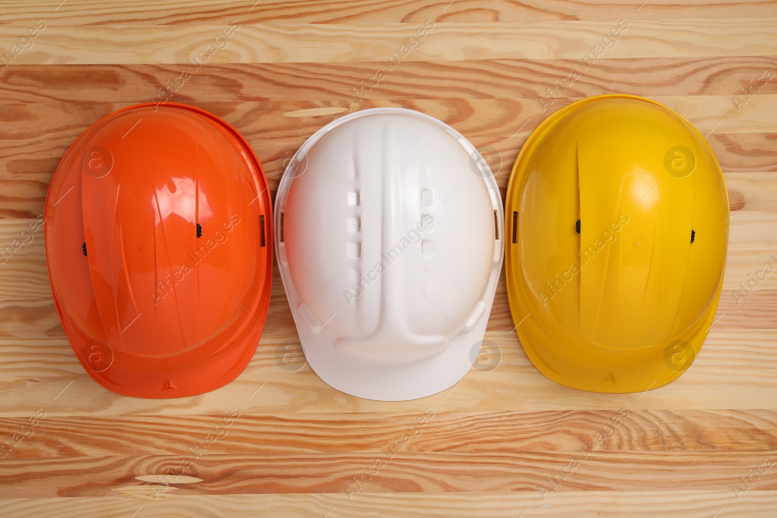 Photo of Hard hats on wooden table, flat lay. Safety equipment