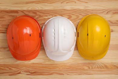 Hard hats on wooden table, flat lay. Safety equipment