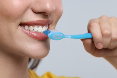 Photo of Woman brushing her teeth with plastic toothbrush on white background, closeup