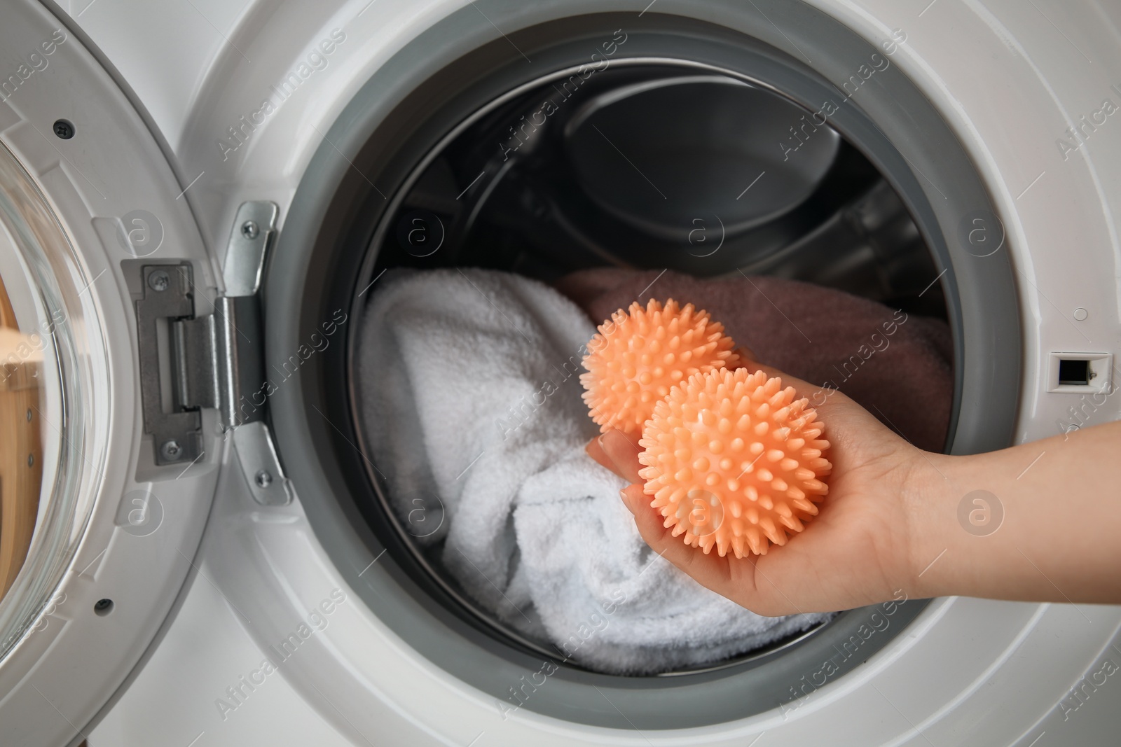 Photo of Woman putting dryer balls into washing machine, closeup