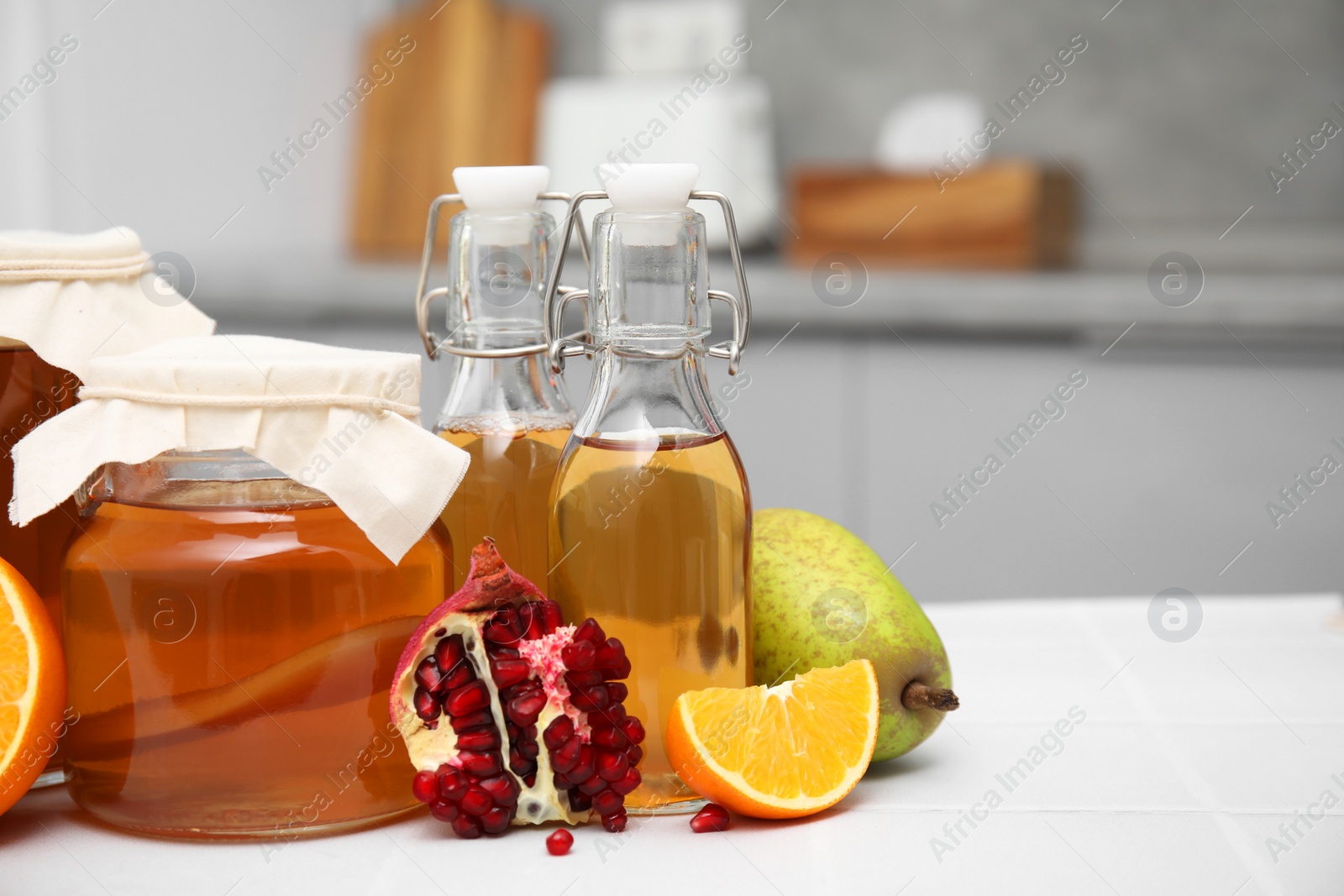 Photo of Homemade fermented kombucha and fresh fruits on white table in kitchen. Space for text