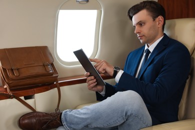 Photo of Businessman working on tablet in airplane during flight