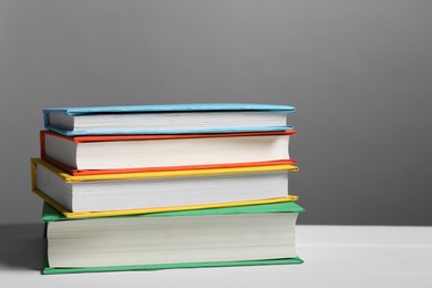 Photo of Different books on white table against gray background. Space for text