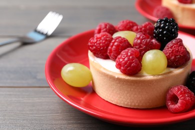 Photo of Delicious tartlet with berries on wooden table, closeup