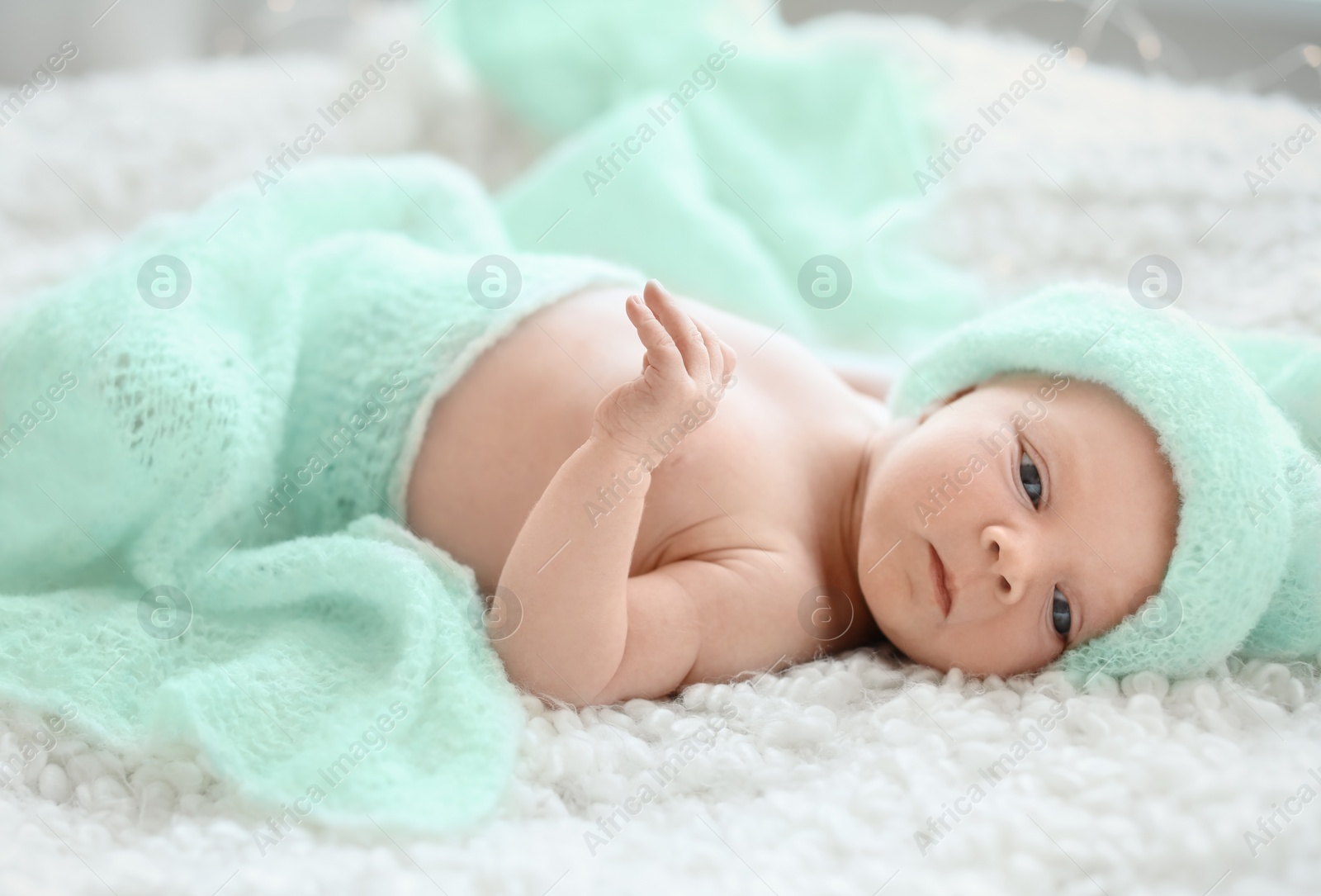 Photo of Adorable newborn baby in warm hat lying on bed