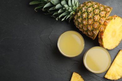 Photo of Delicious pineapple juice and fresh fruit on black table, flat lay. Space for text