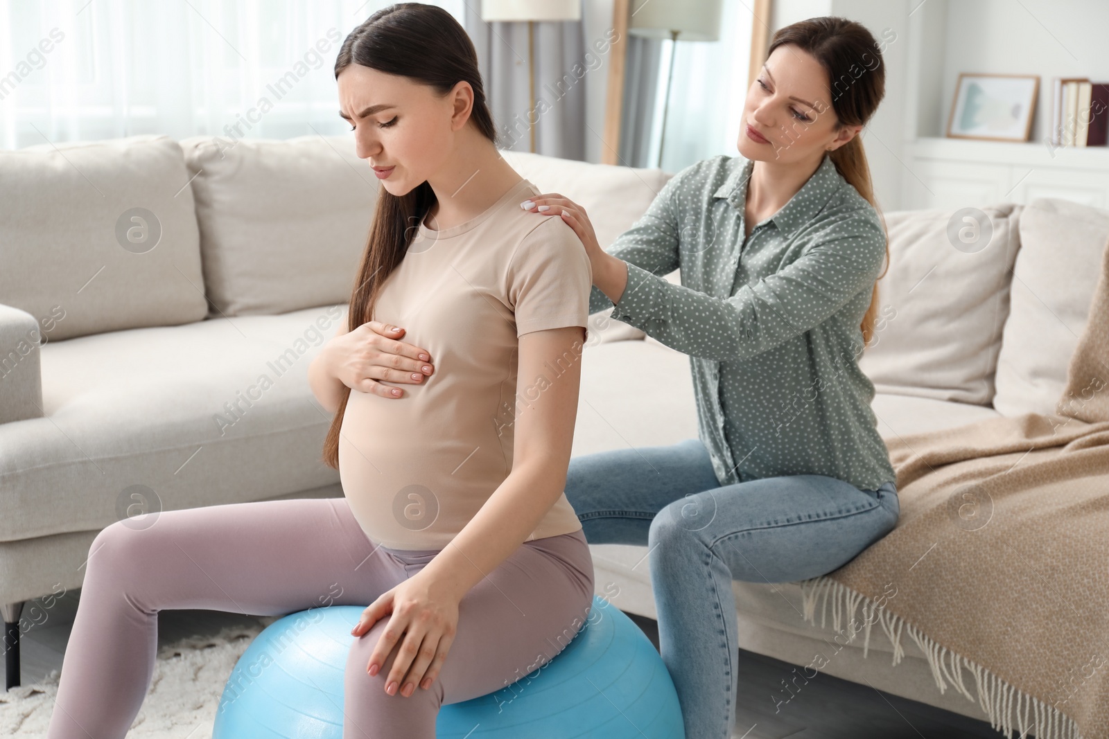 Photo of Doula massaging pregnant woman at home. Preparation for child birth