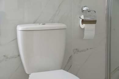Modern toilet and holder with paper roll indoors