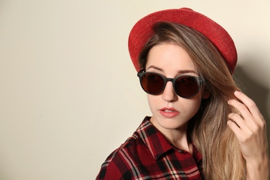 Photo of Young woman wearing stylish sunglasses on beige background. Space for text