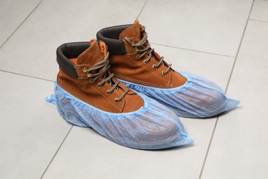 Photo of Men`s boots in blue shoe covers on light floor