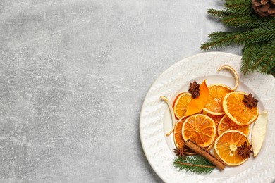 Photo of Flat lay composition with dry orange slices, anise stars and fir branches on light grey table. Space for text