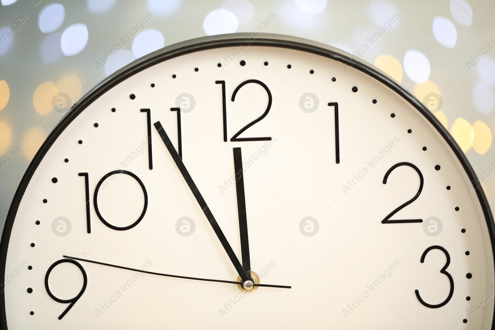 Photo of Clock showing five minutes until midnight on blurred background, closeup. New Year countdown