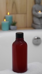 Red bottle of bubble bath on tub indoors