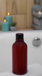 Photo of Red bottle of bubble bath on tub indoors